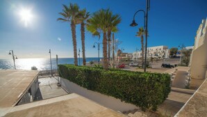 Una passeggiata costiera con palme, lampioni e vista libera sul mare.