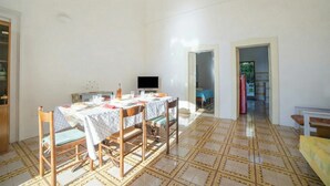 Un'area pranzo con tavolo apparecchiato per quattro persone, televisione e pavimento decorato.