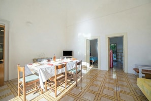 Un comedor con una mesa preparada para cuatro personas, un televisor y un suelo con estampado.