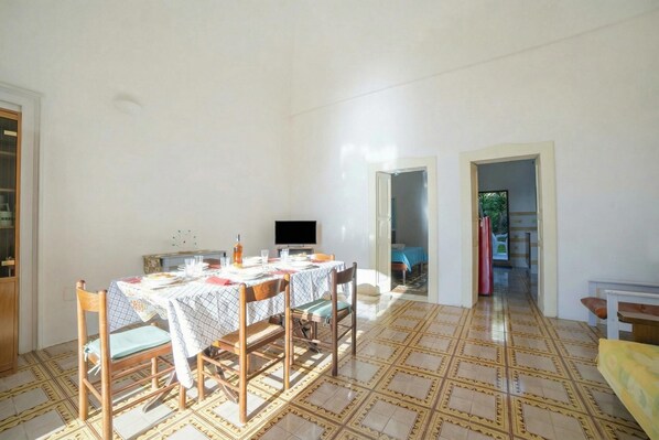 A dining area with a table set for four, a television, and a patterned floor. - Cesarea & Marisole House With Sea View (Santa Cesarea Terme)