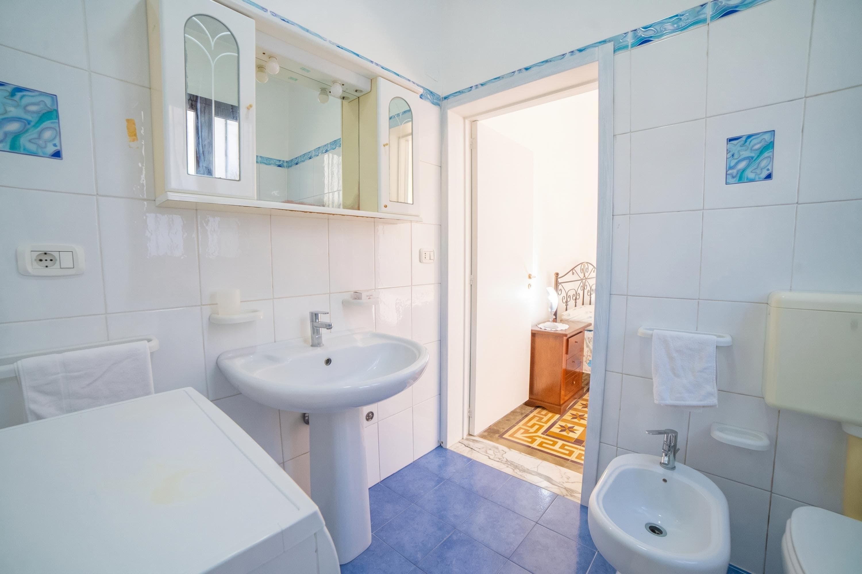 Un baño con dos lavamanos, un espejo, un inodoro y un bidé.