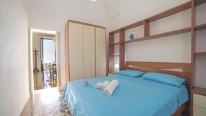 Una camera da letto con un letto, un armadio, un comodino e vista sul balcone.