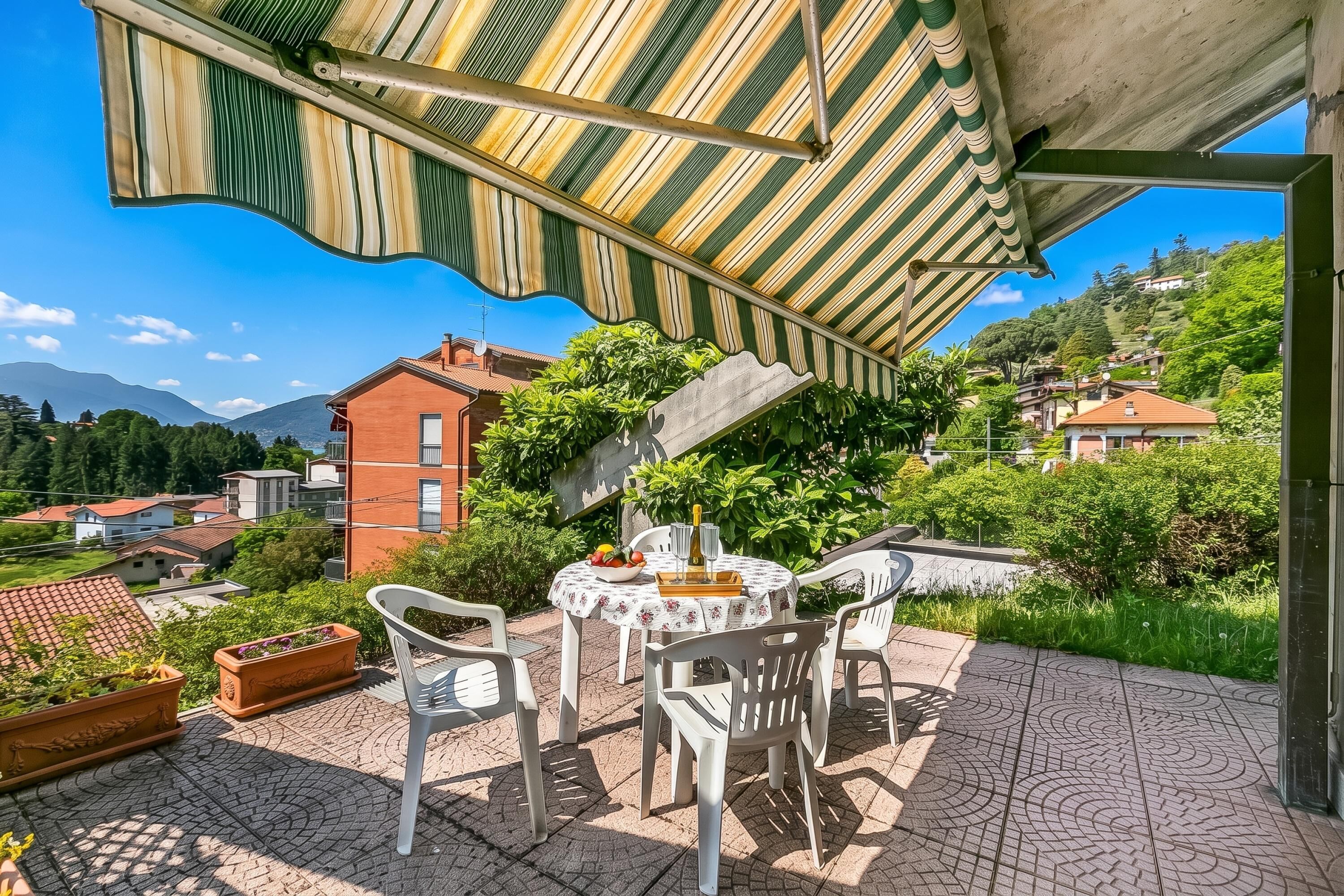A patio with a table, chairs, and a striped awning.