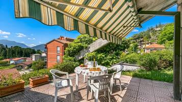 Un patio con tavolo, sedie e un tendone a righe.