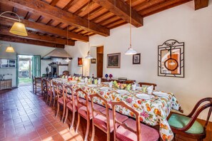 Comedor con una mesa larga dispuesta para una comida, sillas de madera y lámparas colgantes.