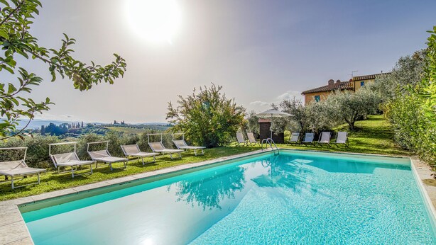 A clear blue swimming pool with lounge chairs and a view of a hill with a building. - Villa Salivolpe Amazing Chianti View (San Casciano in Val di Pesa)