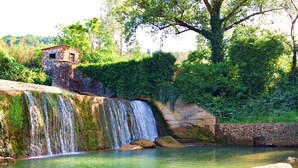A waterfall cascading into a clear pool with a stone structure nearby. - Villa Salivolpe Amazing Chianti View (San Casciano in Val di Pesa)