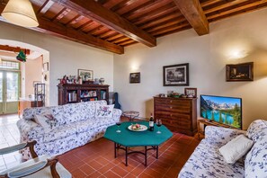 A living room with a sofa, a table, a cabinet, and a painting. - Villa Salivolpe Amazing Chianti View (San Casciano in Val di Pesa)