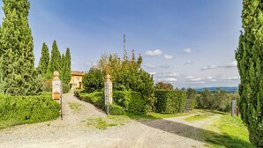A gravel driveway leading to a house with a stone gate and a number sign. - Villa Salivolpe Amazing Chianti View (San Casciano in Val di Pesa)