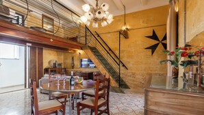 A dining area with a round table, chairs, and a bar counter. - Ta'Battista B&B with pool Ix-Xwejni (Xewkija)