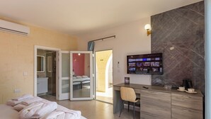 A hotel room with a bed, a desk with a chair, a TV, and a bathroom with a shower and toilet. - Ta'Battista B&B with pool Ix-Xwejni (Xewkija)