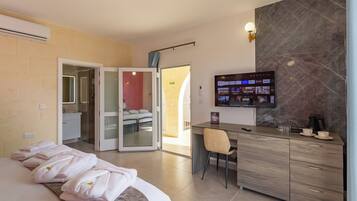 A hotel room with a bed, a desk with a chair, a TV, and a bathroom with a shower and toilet.