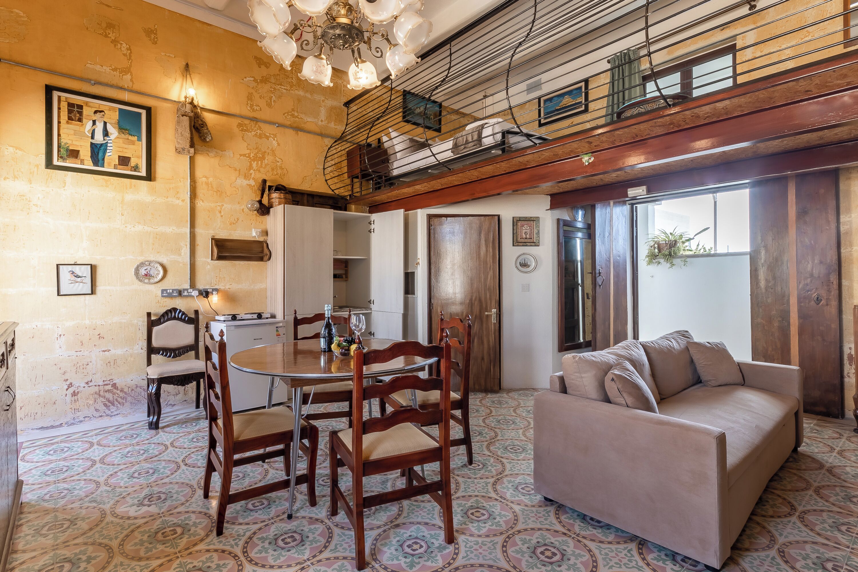 A dining area with a round table, wooden chairs, and a sofa.