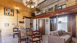 A dining area with a round table, wooden chairs, and a sofa. - Ta'Battista B&B with pool Ix-Xwejni (Xewkija)