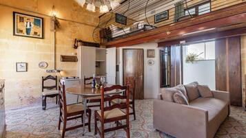 A dining area with a round table, wooden chairs, and a sofa.