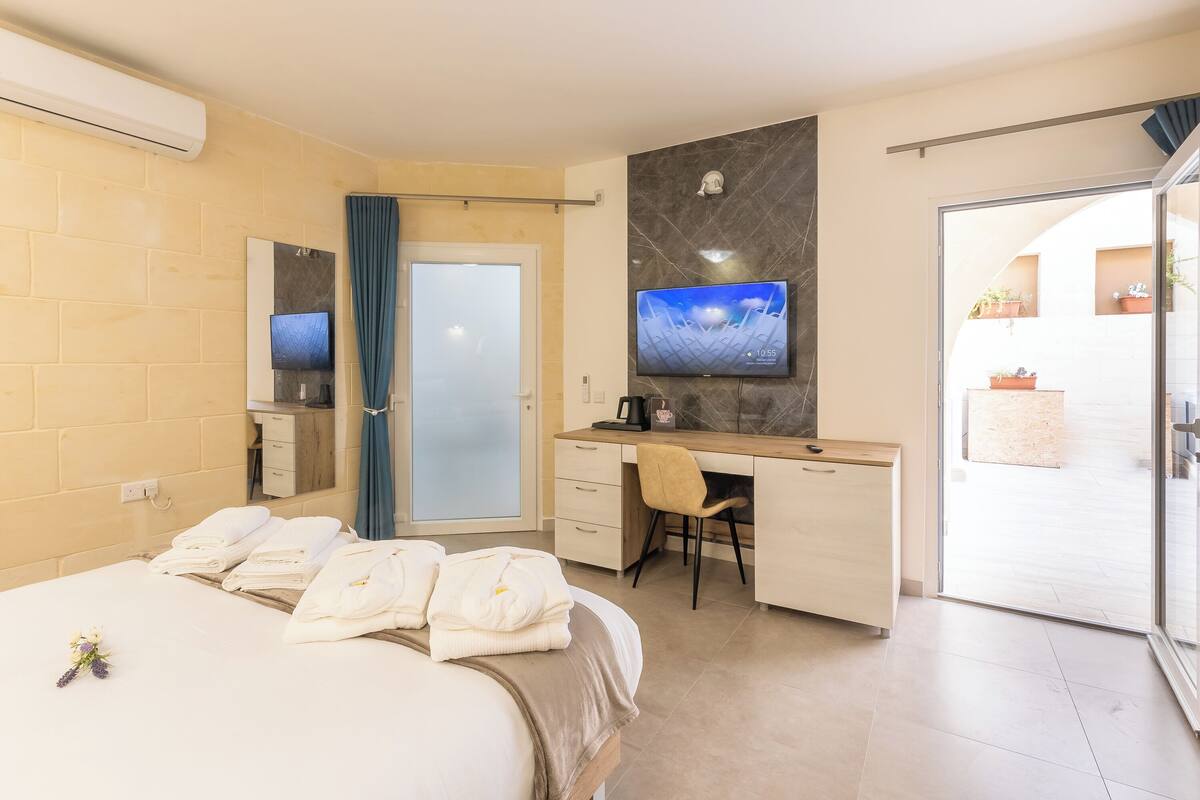 A hotel room with a bed, a desk, a TV, and a bathroom.