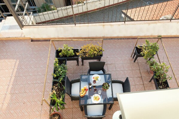 An outdoor patio with a table and chairs, surrounded by potted plants. - La Finestra Sul Mare Sanremo (Sanremo)