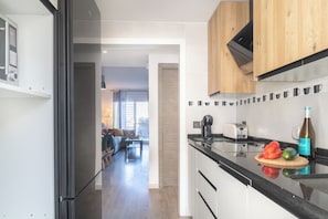 A modern kitchen with wooden cabinets, a black countertop, and a cutting board with vegetables.