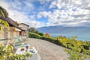 A patio with a table set for dining, overlooking a mountainous landscape and a body of water. - Gargnano Apartments (Gargnano)