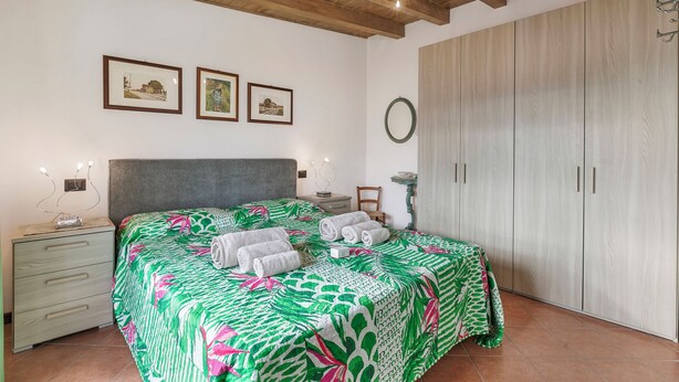 A bedroom with a bed, a nightstand, a dresser, a wardrobe, and framed pictures on the wall. - Gargnano Apartments (Gargnano)