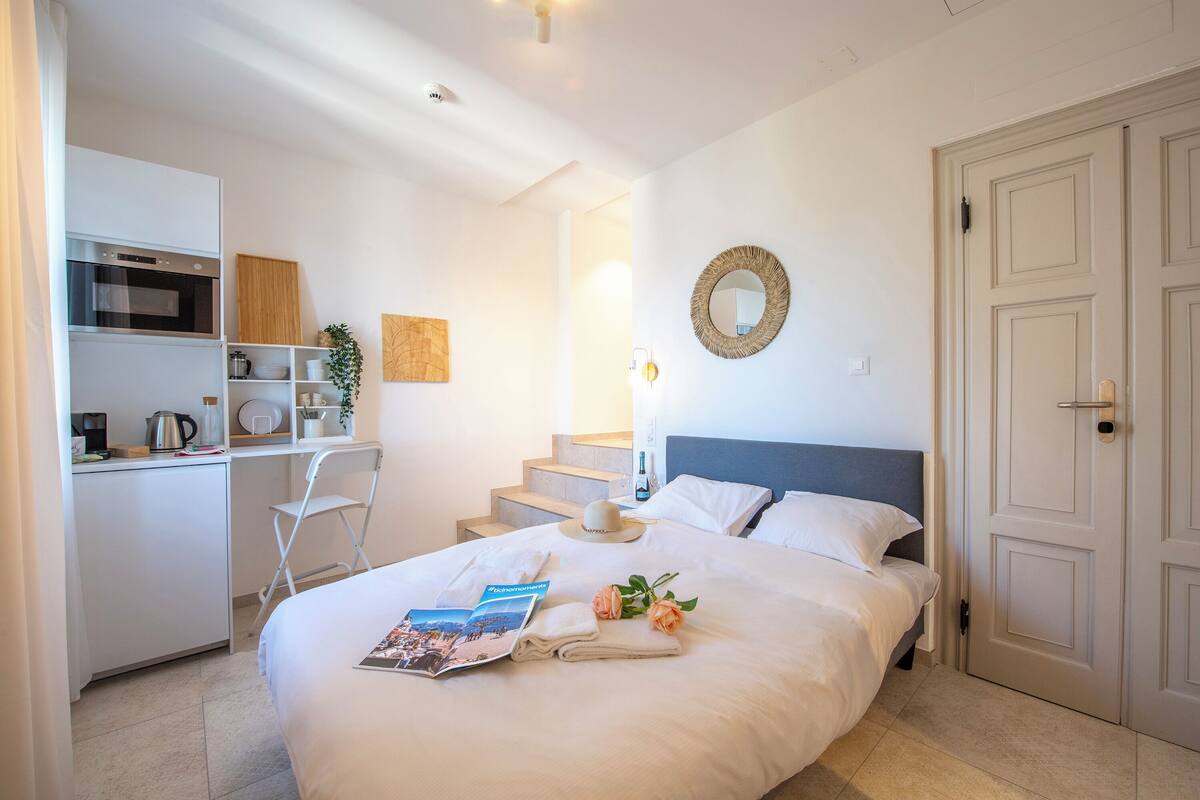 Une chambre d’hôtel comprenant un lit, un bureau avec un micro-ondes, une chaise et un escalier menant à une autre pièce.