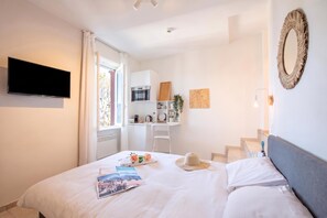 A hotel room with a bed, a flat-screen TV, a desk with a microwave, a chair, and a staircase. - Tesori Della Vetta (Lugano)