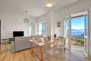 Un espace de vie moderne comprenant un coin repas, un canapé, un téléviseur et un balcon avec vue.