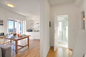 A modern kitchen with a dining table, white cabinets, and a view of the outdoors. - Luce Lake View on Stresa Hill (Stresa)