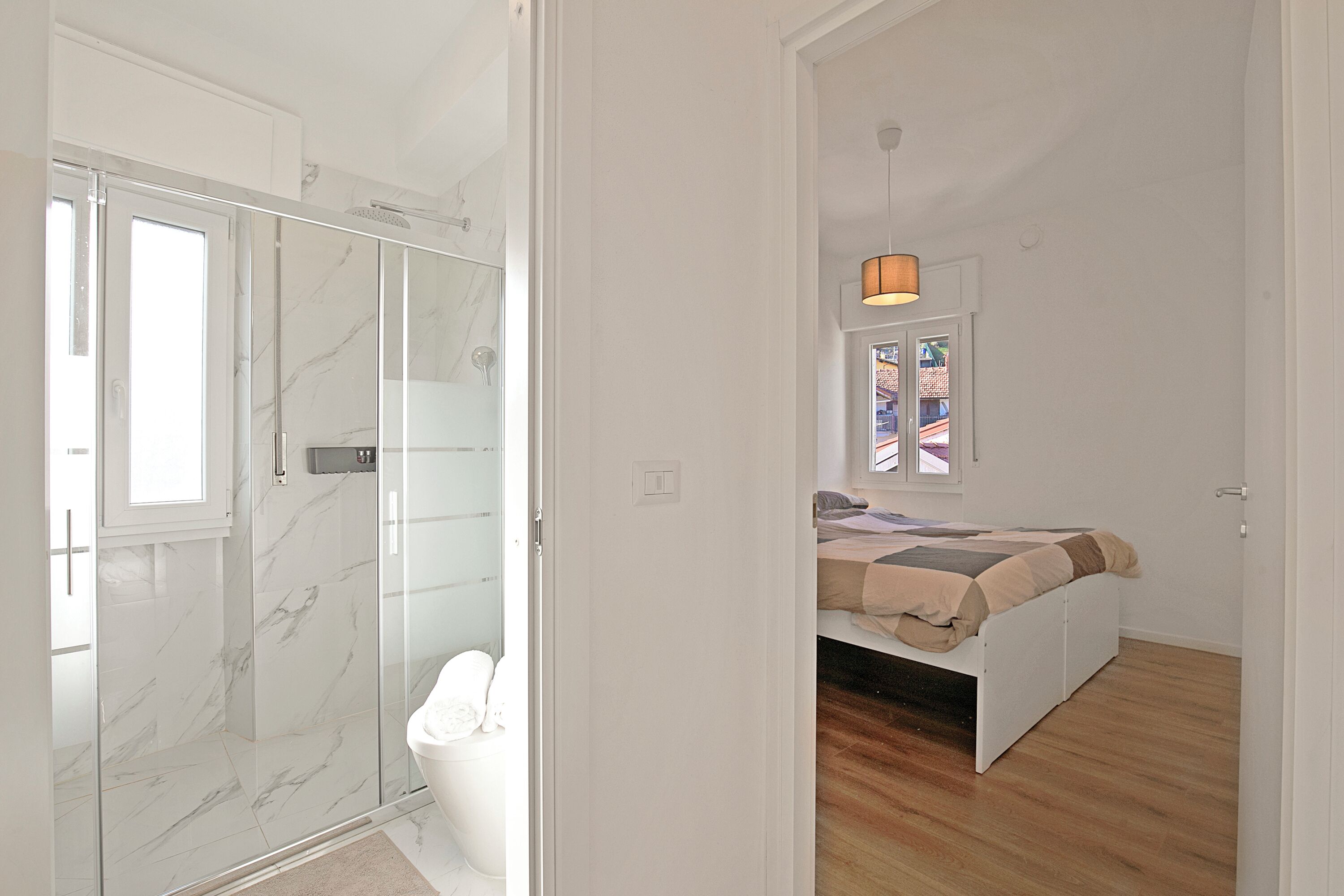 Une chambre à coucher avec un lit, une fenêtre donnant sur un beau paysage et un espace douche doté de portes en verre.