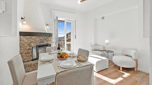 A dining area with a stone fireplace, white furniture, and a view through an open door. - Luce Lake View on Stresa Hill (Stresa)