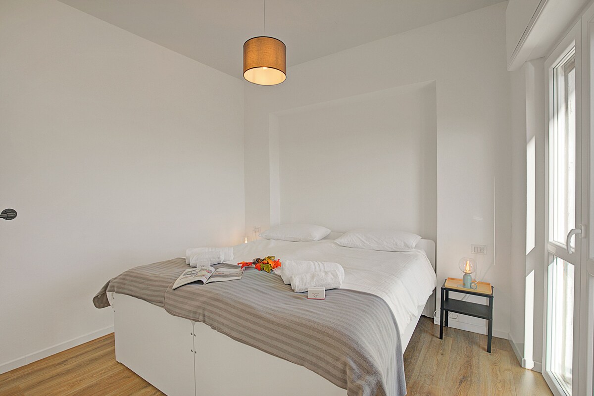 Ein modernes Schlafzimmer mit Bett, Nachttisch und einer Pendelleuchte.
