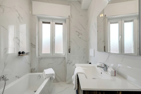 Ein modernes Badezimmer mit einer Badewanne, einem Waschbecken und einem großen Spiegel.