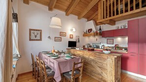 Un tavolo da pranzo in legno con sedie, un'isola della cucina e un armadietto rosso.