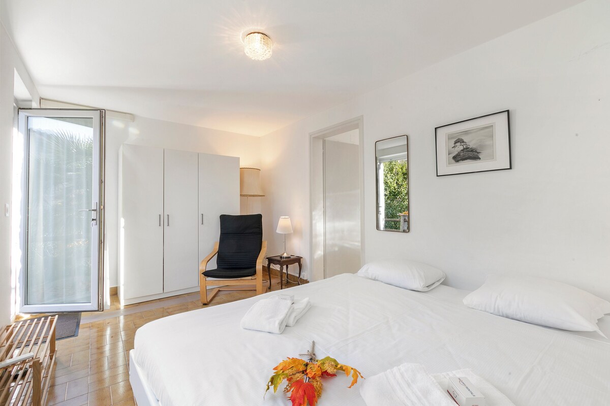 A hotel room with a large bed, a chair, a desk, and a wardrobe.