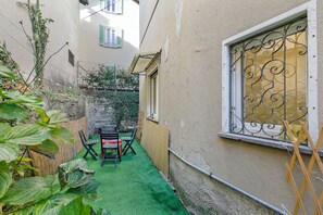 Relax in this serene outdoor space with a table and chairs, surrounded by lush greenery and a view into the building.