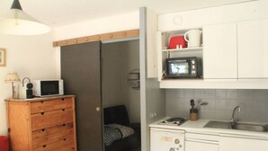 Una cocina compacta con microondas, un lavamanos y un mueble pequeño.