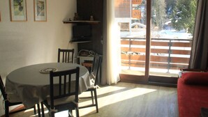 Un comedor con una mesa redonda, sillas y un televisor en un estante.