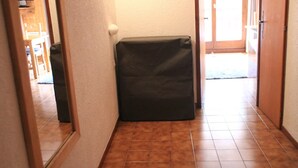 Käytävän lattia on laatoitettu, oikealla puolella on ovi ja keskellä pieni musta esine.