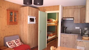 A compact room with a bunk bed, a microwave, a small kitchen area, and a wooden cabinet. - Apartment in Chatel in ski resort (Châtel)