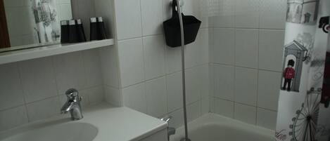 A bathroom with a white sink, a mirror, and a shower area.