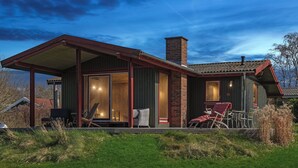 A modern house with a covered porch, large windows, and outdoor seating. - Cozy cottage with a beautiful view. (Tranekær)