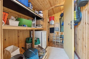 Eine kleine Küche mit Holzwänden, einem Kühlschrank und unterschiedlichen Aufbewahrungsbehältern.
