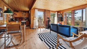 A wooden interior with a dining area, kitchen, and seating area with a view. - Cozy cottage with a beautiful view. (Tranekær)