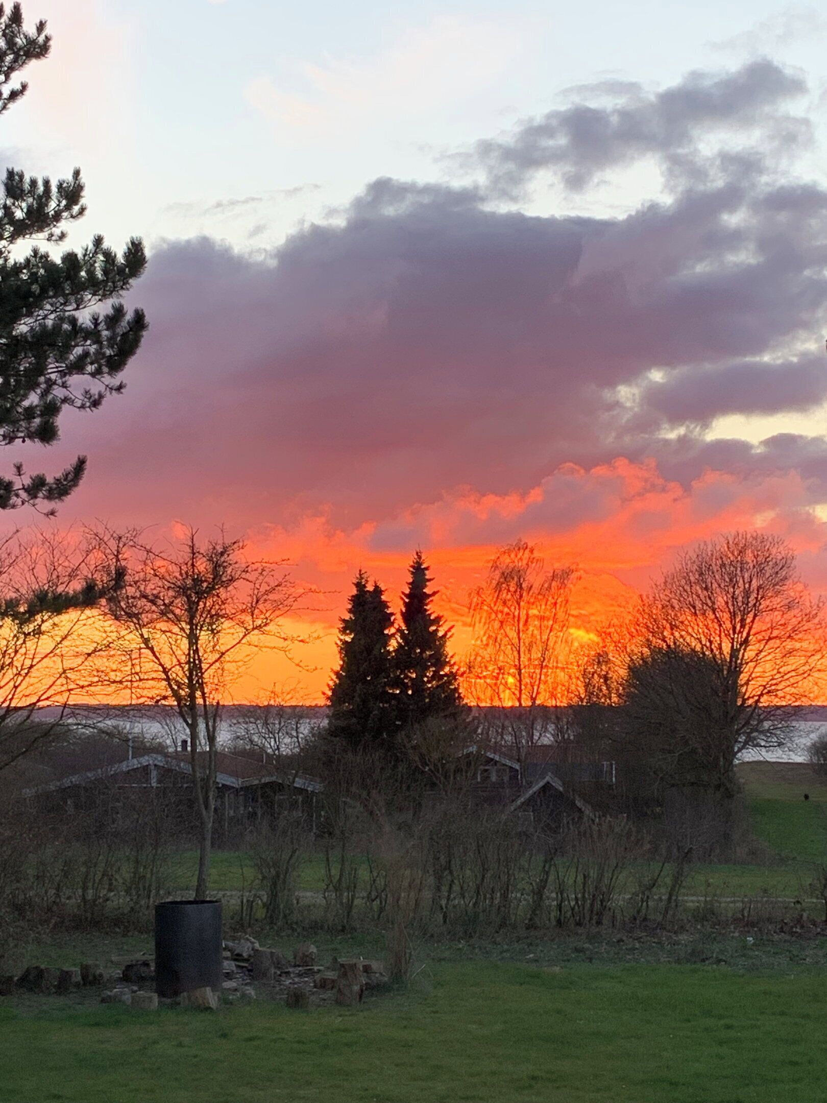Solnedgang over et landligt landskab med huse og træer.