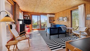 A cozy room with a wooden ceiling, a checkered floor, a blue sofa, and a wooden chair. - Cozy cottage with a beautiful view. (Tranekær)