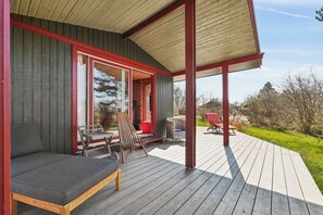 A covered outdoor deck with a sofa, chairs, and a table.