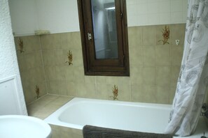 A bathroom with a bathtub, a window, and a shower curtain.