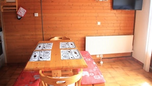 Un intérieur en bois avec une table dressée pour le repas, un téléviseur fixé au mur et un radiateur.