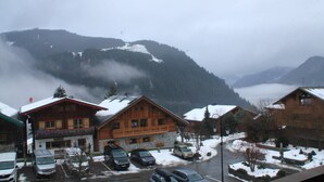 Un village de montagne enneigé, avec des bâtiments en bois et des voitures garées.