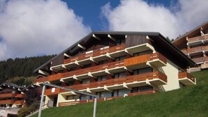 A multi-story hotel with balconies and a mountainous backdrop. - Apartment in Châtel near Cable Car (Châtel)